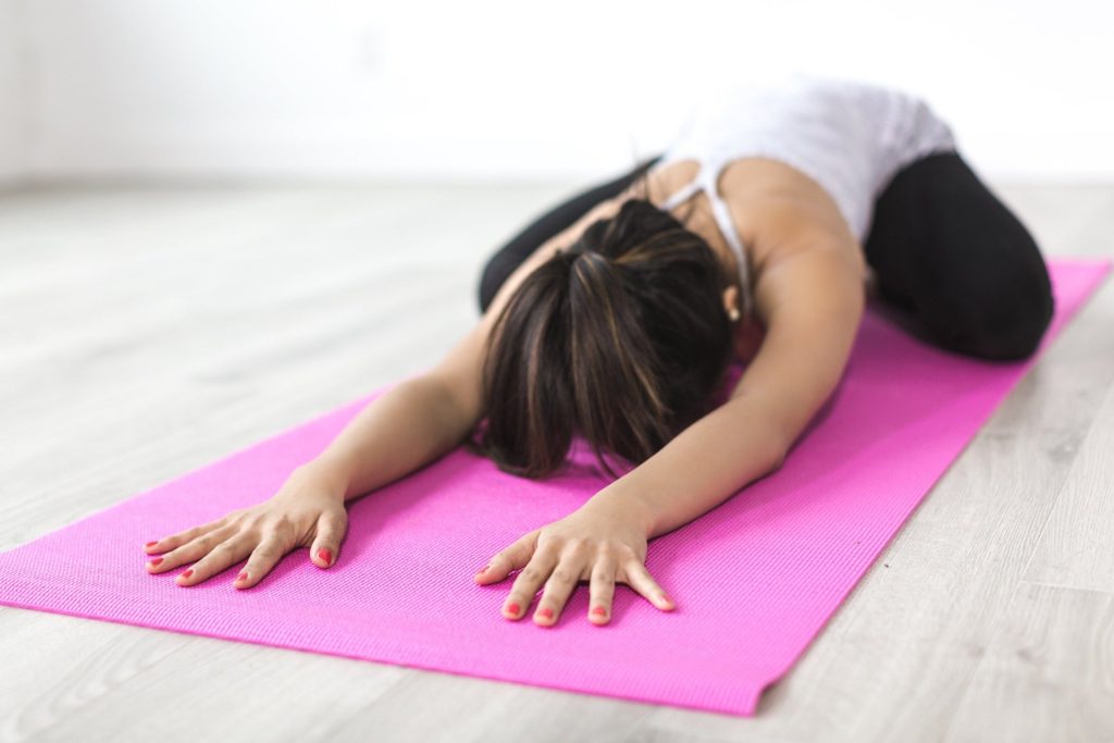 Kvinde dyrker yoga på matte
